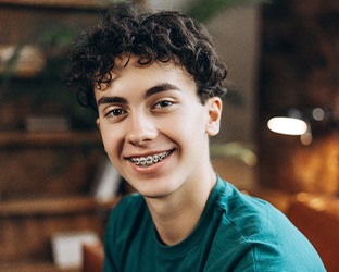 a smiling child with braces wearing a teal shirt