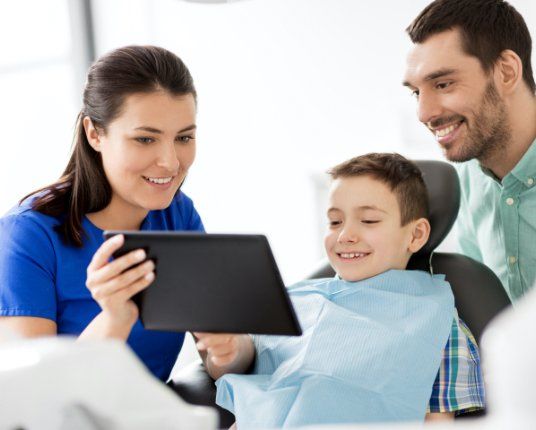 Father child and dental team member looking at smile images