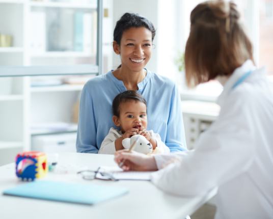 Mother holding child in lap during her infant's first dental visit