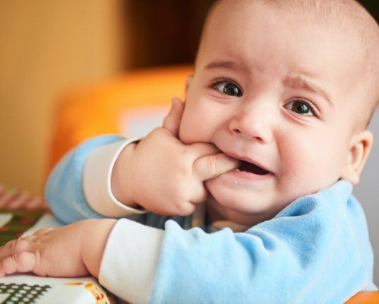 Teething baby chewing on fingers