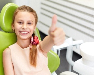 Female child giving thumbs up visiting emergency dentist in Hamilton, ON