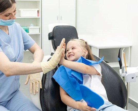 Little girl giving high-five to dental team member