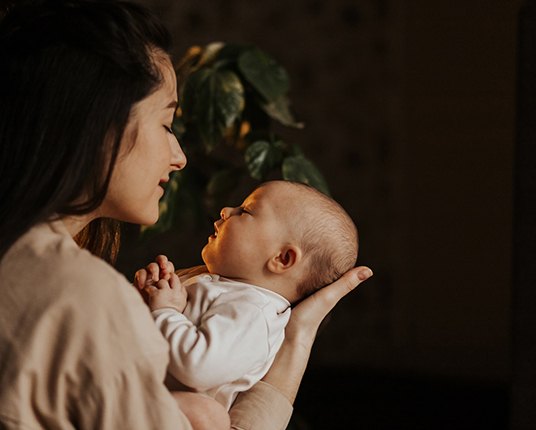 young woman holding a baby with a lip tie in Hamilton 