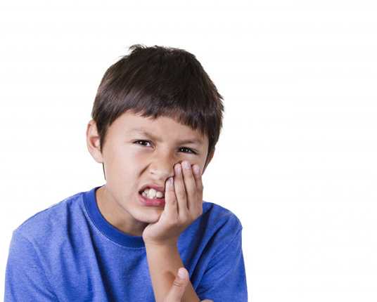 boy with a toothache holding his cheek in pain 
