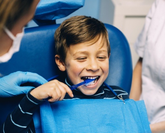 Child using toothbrush during oral health risk assessment