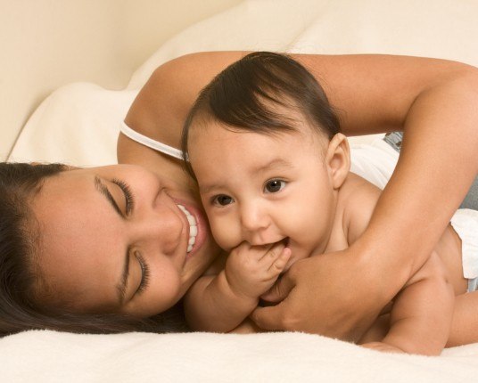 Mother laughing and holding teething baby