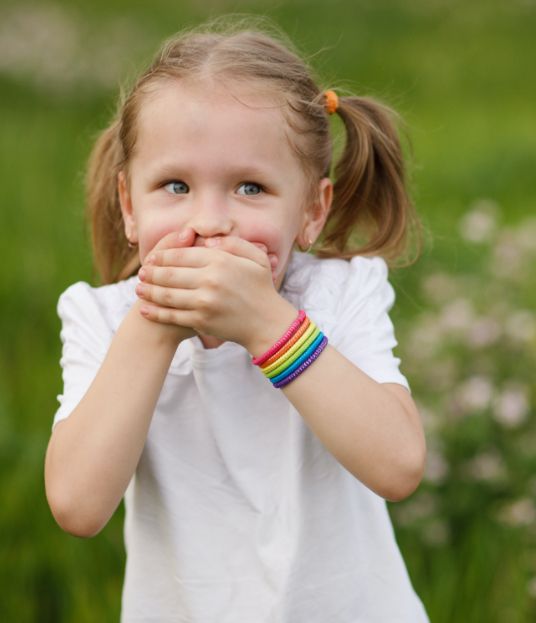 Young girl covering her mouth before emergency dentistry