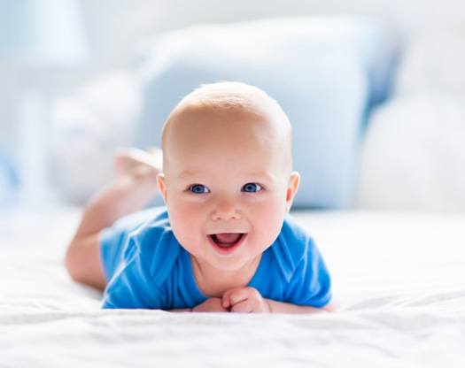 Baby in blue onesie after tongue-tie treatment in Hamilton  