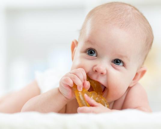 Baby using teething ring before dentistry for infants visit