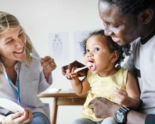 Child learning to brush teeth during dentistry for toddlers visit