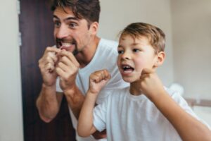 Parent and child flossing their teeth. 